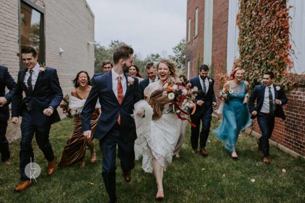 Vintage brewing fall wedding, with joyful bride and groom running, dahlia bouquet and fur details.