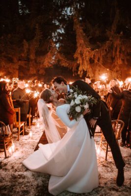 New years eve wedding sendoff with sparklers, outdoor ceremony, dramatic kiss, fir backdrop.